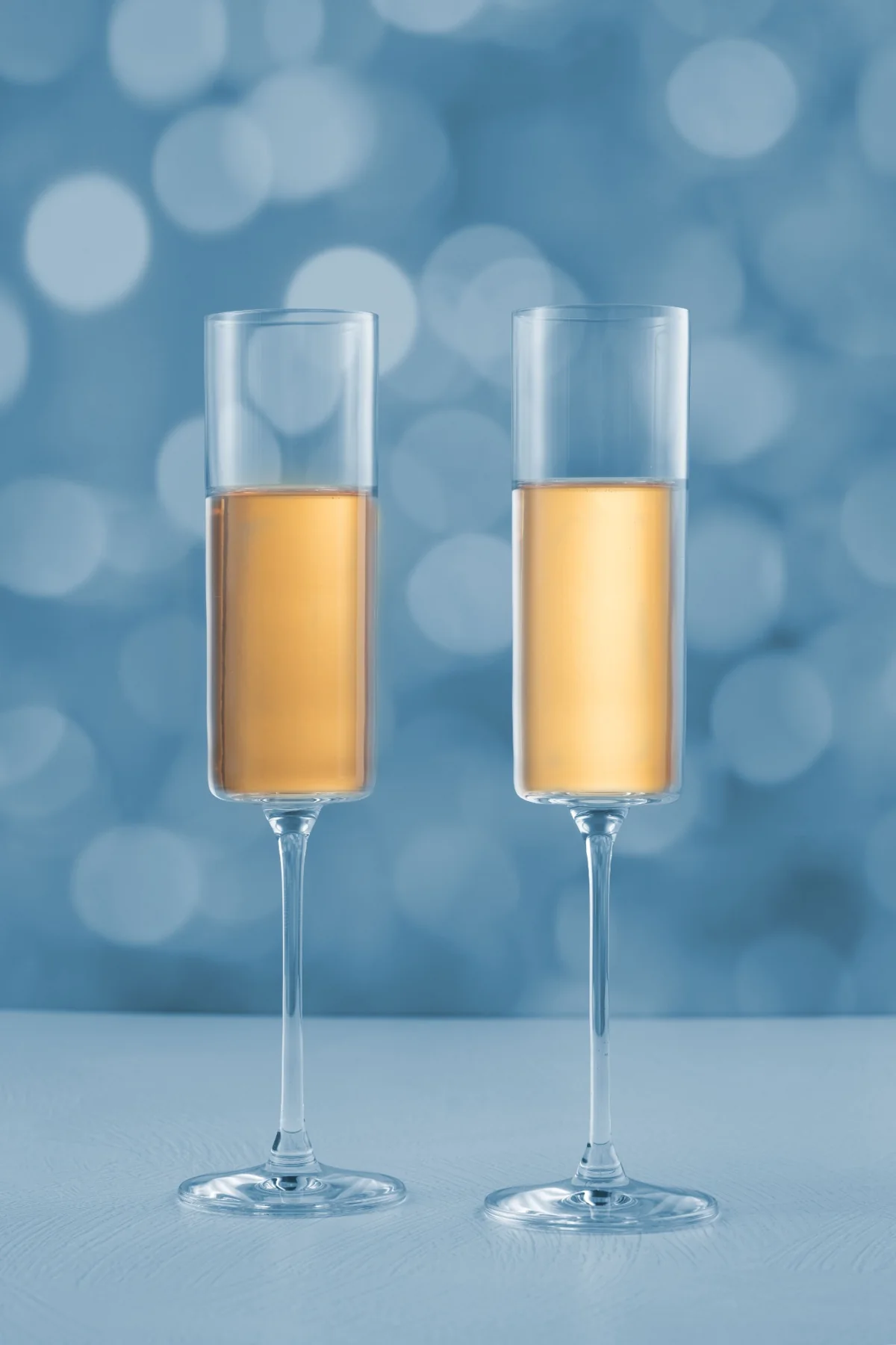 Two champagne flutes against a soft blue background