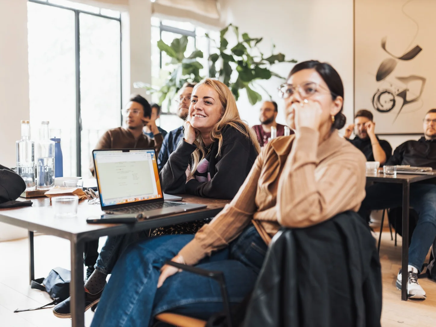 Attendees listening during a workshop with laptops and notebooks on their tables.